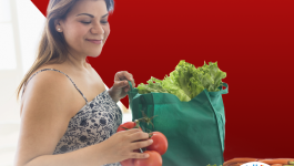 download Square image of woman taking groceries of out a bag (eating healthy)  with the words Get Down With Your Blood Pressure (Entrale a bajar tu presion) in Spanish and the Hispanic Heritage Month logo